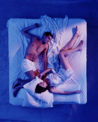 Couple sleeping at opposite ends of the bed, overhead view