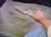 Use trowel to throw sand on wall