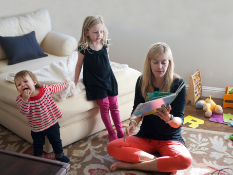 Mother reading to toddler and girl at home