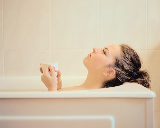 Woman Lying in a Bathtub Holding a Mug