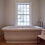 A bathtub sits in the "hers" bathroom in the master suite of