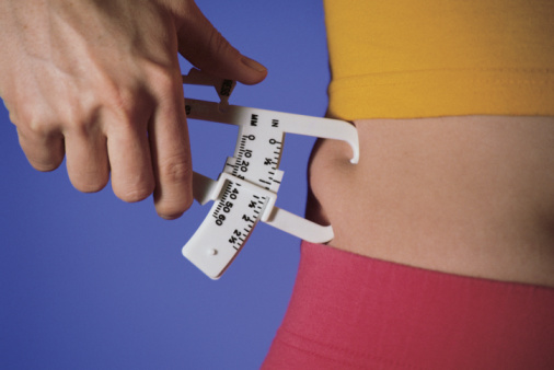 Woman measuring percentage of body fat on waist