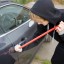 Burglar prying car window open with crowbar