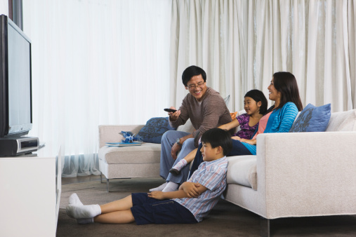 Asian family watching tv in their home