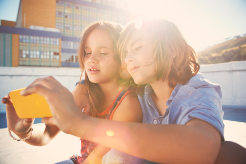 Girl and boy (8-10) looking at smart phone