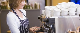 Woman making coffee in restaurant smiling