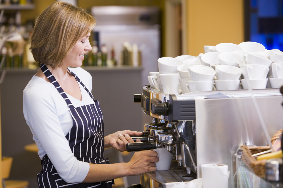 Woman making coffee in restaurant smiling