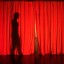 Female silhouette behind theatrical red curtains