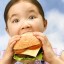 Little girl munching on a large burger