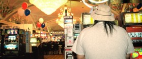 Man playing slot machine in casino, rear view