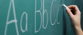 Woman writing alphabet on chalkboard, close-up
