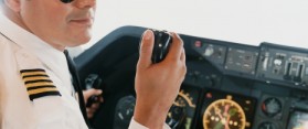 Pilot Sitting in the Cockpit Holding a Radio