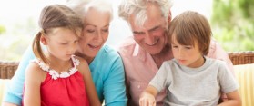 Grandparents And Grandchildren Reading Book On Garden Seat