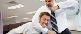 Two businessmen fighting in office, one in headlock