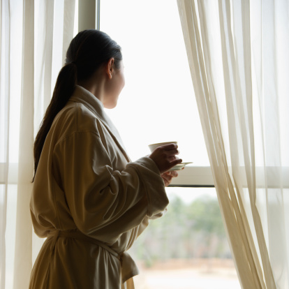 Woman in bathrobe looking out window