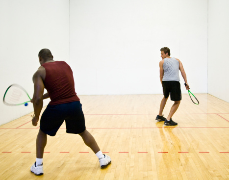 Two men playing racquetball indoors