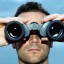 Man looking through binoculars outdoors, close-up