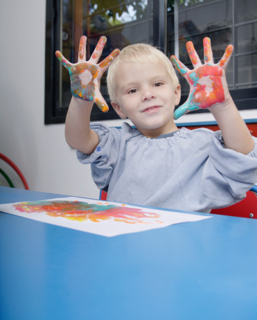 Boy finger-painting in classroom
